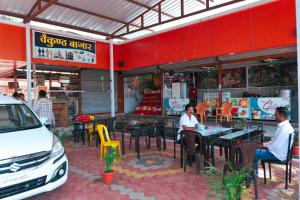 2 personnes assises à l'extérieur d'un restaurant dans l'établissement ISKCON Pandharpur's Chandrabhaga Guest House, à Pandharpur