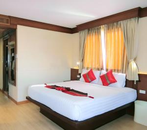 a bedroom with a large white bed with red pillows at Sira Boutique Chiang Mai in Chiang Mai
