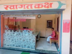 une femme assise sur une chaise devant un magasin dans l'établissement ISKCON Pandharpur's Chandrabhaga Guest House, à Pandharpur