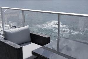 una silla y una mesa en un balcón con vistas al océano en Apt 'A Gaioa' in 'The Cliff Coast Accomodation', en Paul do Mar