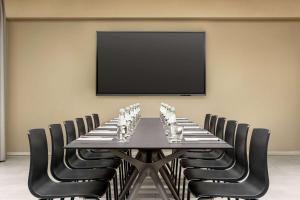 a conference room with a table with chairs and a flat screen tv at Amedia Hotel Milan, Trademark Collection by Wyndham in Milan