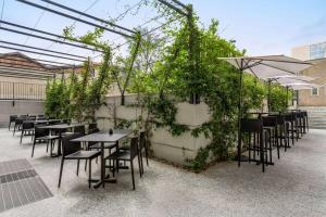 a row of tables and chairs with plants on a patio at Amedia Hotel Milan, Trademark Collection by Wyndham in Milan