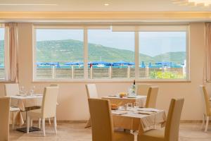 a restaurant with tables and chairs and a large window at Hotel Portoconte in Porto Conte