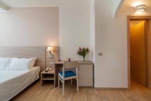 a hotel room with a bed and a desk with a chair at Hotel Portoconte in Porto Conte