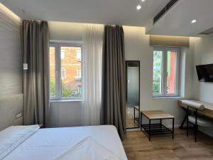 1 dormitorio con 1 cama, escritorio y ventanas en D Rooms en Tirana