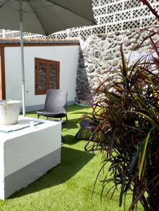 a patio with a chair and an umbrella and grass at La casa de Isabel in Mazo