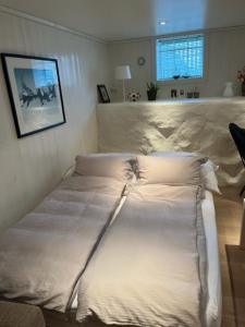 a bed with white sheets and pillows in a bedroom at Hybel med bad in Egersund