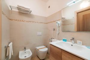 a bathroom with a sink and a toilet and a mirror at Hotel Portoconte in Porto Conte