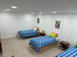 Habitación con 2 camas y sábanas azules y blancas. en Aparment Almudena en Madrid