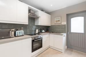 a white kitchen with white cabinets and a window at Cheerful 3 bed in the heart of Fethard village in Fethard on Sea