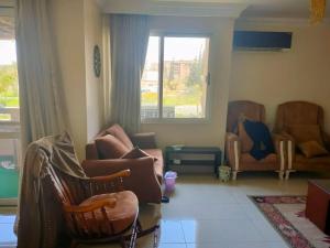 een woonkamer met stoelen, een bank en een raam bij Cozy apartment with an excellent garden view in Caïro