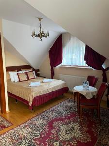 1 dormitorio con cama, mesa y lámpara de araña en Pensjonat Szach, en Krynica-Zdrój