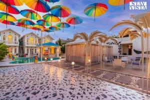 a bunch of umbrellas hanging over a pool at StayVista's Udaan Manor with Outdoor Pool, Jacuzzi & Lush Lawn with Gazebo & Bar in Chandīgarh