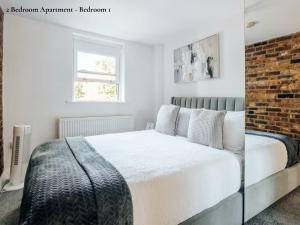 um quarto com uma cama e uma parede de tijolos em Lux Bermondsey Apartments Near Tower Bridge em Londres