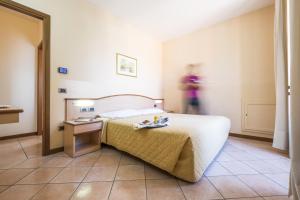 a hotel room with a bed and a person in the background at Residence XX Settembre in Alba