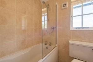 baño con bañera, aseo y ventana en The Bothy - Charming home on a working farm en Faversham