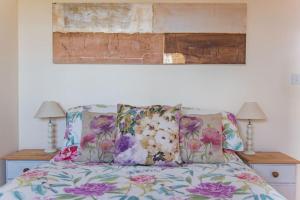 a bed with pillows and a painting on the wall at The Bothy - Charming home on a working farm in Faversham
