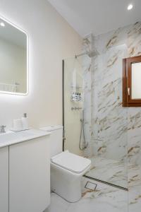 a white bathroom with a toilet and a shower at Infinity View Apartment in Naxos Chora