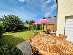 - une table en bois avec un parasol rose dans la cour dans l'établissement Superbe maison spacieuse avec jardin, à Angers