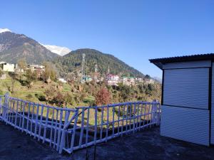 a balcony with a blue fence and a mountain at Soul Healingg World Retreat in Dharamshala