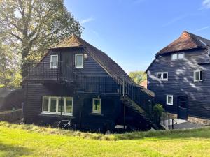 a large black house with a staircase on the side of it at The Hay Loft in Warnham