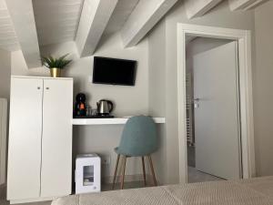 a bedroom with a blue chair and a tv on the wall at Casa Barú Scicli in Scicli