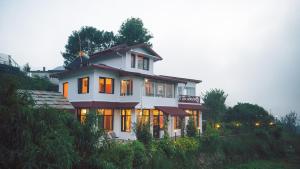 a house on a hill with its lights on at SaffronStays The Clairmont Cottage,Mukteshwar in Mukteshwar