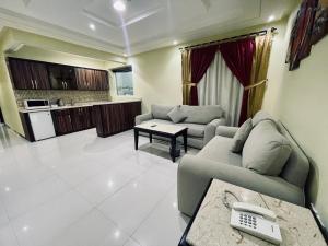 a living room with two couches and a kitchen at شقق توليب الروضه للشقق المخدومة in Riyadh