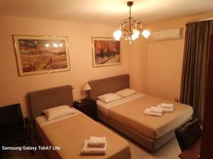 a hotel room with two beds and a chandelier at VILLA AVATOS - Near to the Port of Rafina and the Airport of Athens in Áyios Spirídhon