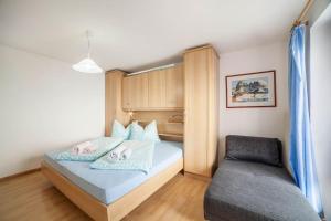 a small bedroom with a bed and a couch at Oberkapillhof in Meltina