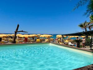 een groot zwembad naast een strand met parasols bij Das Casa Liguria - Luxuriöses Ferienhaus nur 5 Gehminuten vom Strand - Cinque Terre & Sestri Levante in Lavagna