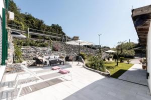 een patio met stoelen en een stenen muur bij Das Casa Liguria - Luxuriöses Ferienhaus nur 5 Gehminuten vom Strand - Cinque Terre & Sestri Levante in Lavagna