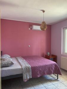 a bedroom with a bed and a pink wall at Seaside Blue Coast Apartment in Anavissos
