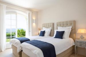 two beds in a bedroom with a large window at Golfvilla Riviera in Grimaud