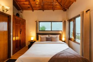 a bedroom with a large bed and two windows at SaffronStays The Clairmont Cottage,Mukteshwar in Mukteshwar