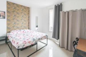 a bedroom with a bed and a table and a window at Cozy & modern flat next to M12 Front Populaire in Saint-Denis
