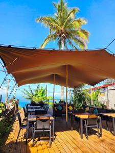 a large umbrella on a deck with tables and chairs at Domaine de l'Anse in Petite Île