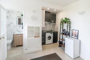 a white kitchen with a sink and a washing machine at Cozy & modern flat next to M12 Front Populaire in Saint-Denis