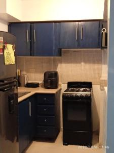 a kitchen with a black stove and blue cabinets at Apartamento Familiar y tranquilo in Pantoja
