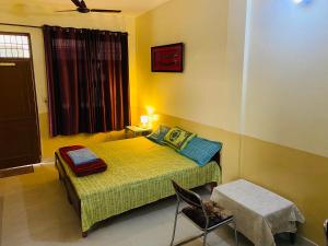 a small bedroom with a bed and a chair at Negi Lodge Chandigarh in Chandīgarh