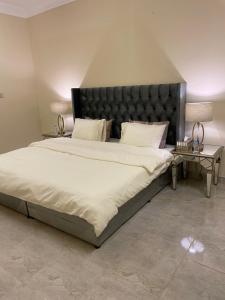 شقة فندقية ثلاث غرف نوم وغرفة معيشة ومطبخ ومدخل خاص وباركنج سيارة في Riyadh Al Khabra: سرير كبير مع اللوح الأمامي الأسود في غرفة النوم