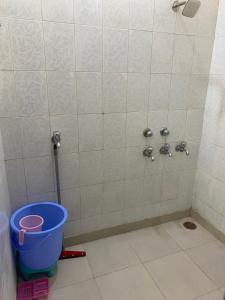 a bathroom with a shower with a bucket on the floor at Negi Lodge Chandigarh in Chandīgarh