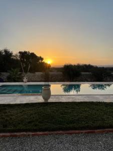 een zonsondergang boven een zwembad met een potplant bij Villa Des Arganiers in Essaouira