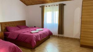 een slaapkamer met een bed met paarse lakens en een raam bij Vila Deda in Lezhë