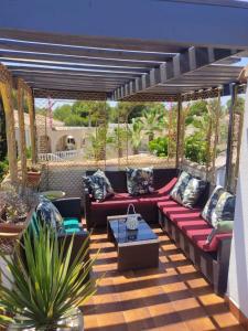 eine Terrasse mit einem roten Sofa und einem Tisch in der Unterkunft Villa Castillo Nuevo with optional Heated Private Pool in San Miguel de Salinas