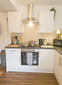 a kitchen with white cabinets and a sink at Principality Suites - Two Bed Apartment by Property Promise in Cardiff