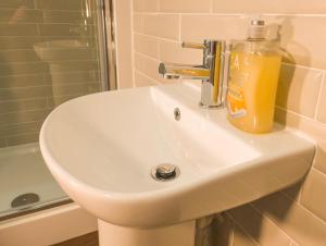 a bathroom sink with a bottle of orange juice on it at Principality Suites - Two Bed Apartment by Property Promise in Cardiff