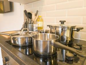four pots and pans on a stove in a kitchen at Principality Suites - Two Bed Apartment by Property Promise in Cardiff