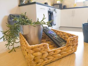 a basket with a remote control and a plant on a table at Principality Suites - Two Bed Apartment by Property Promise in Cardiff
