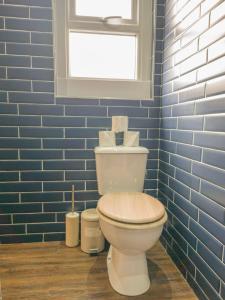 a bathroom with a toilet with a window and blue tiles at Principality Suites - Two Bed Apartment by Property Promise in Cardiff